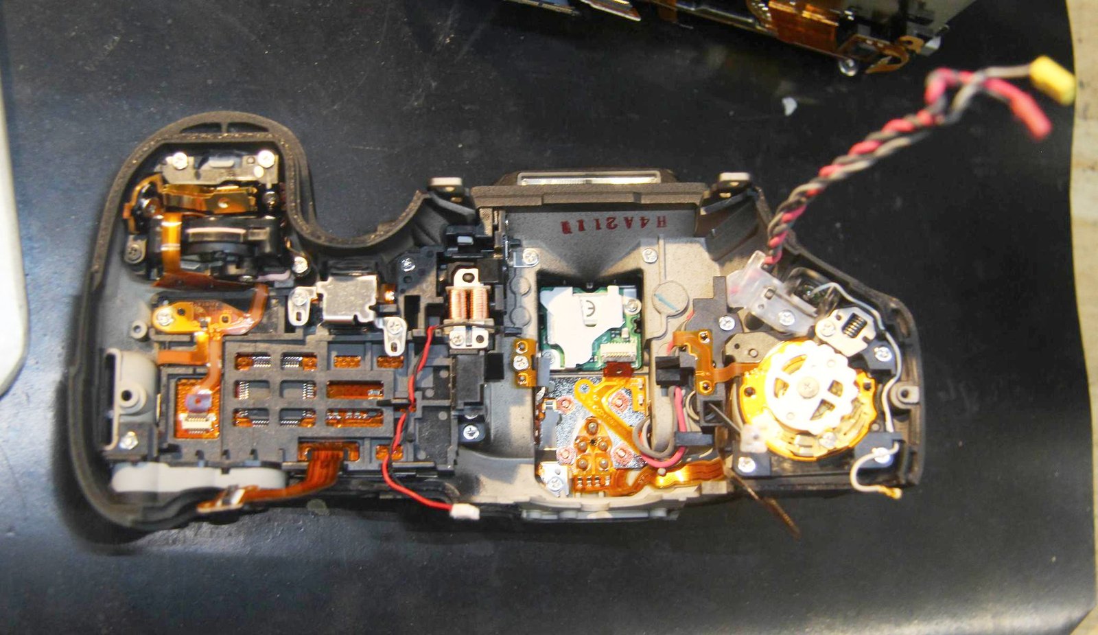 Top section, on it's back. Shutter button is on the top left.